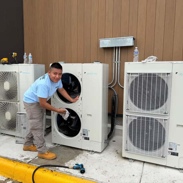 Gask technician cleaning a bank of ductless mini-split condensers on a rooftop pad